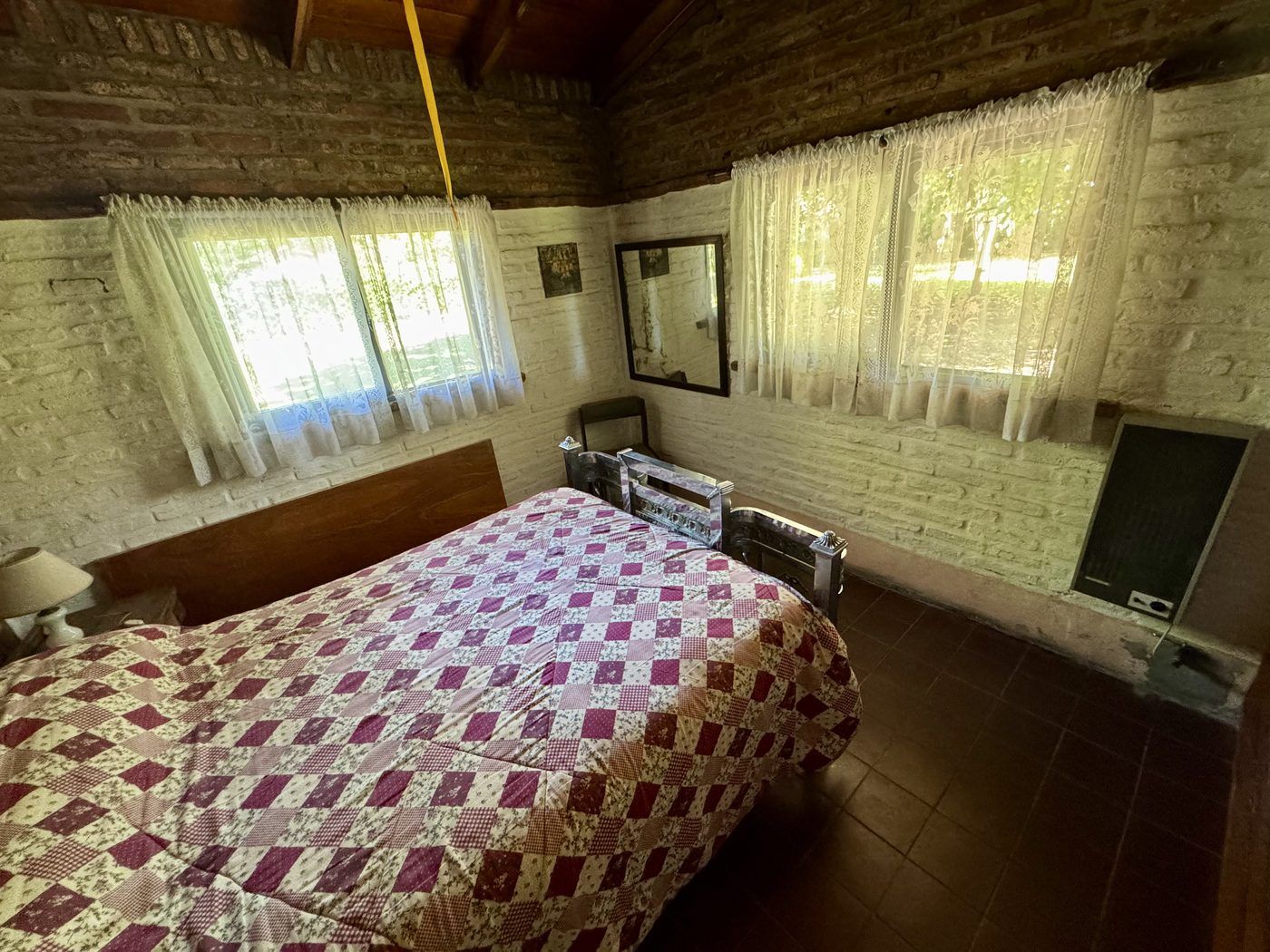 Dormitorio con cama de dos plazas, paredes de ladrillo y techo de madera