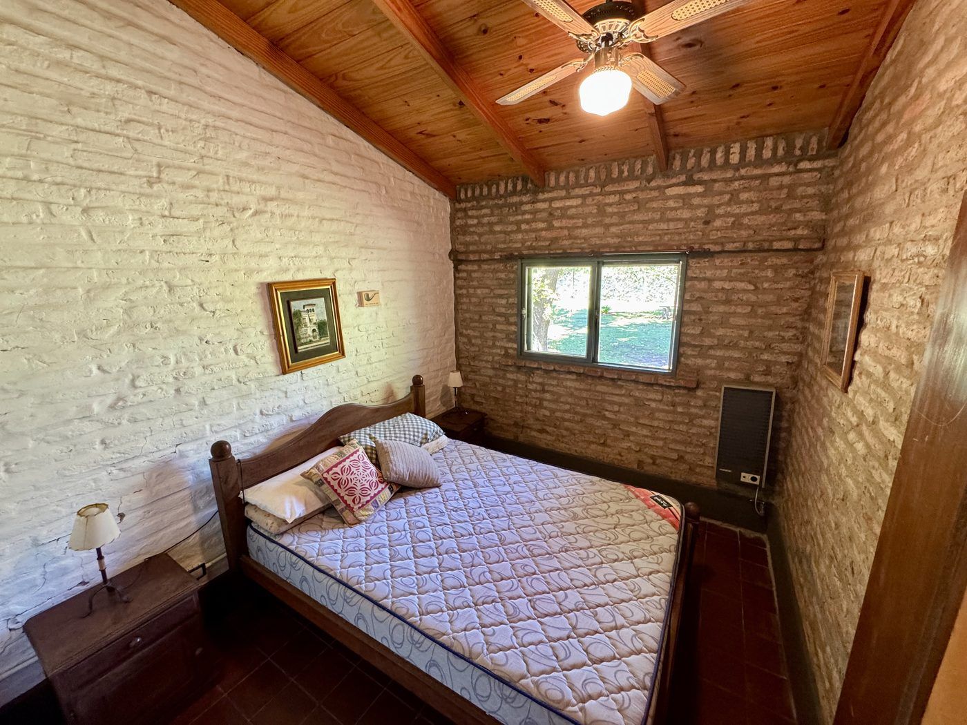 Dormitorio con cama de dos plazas y ventana con vista al verde