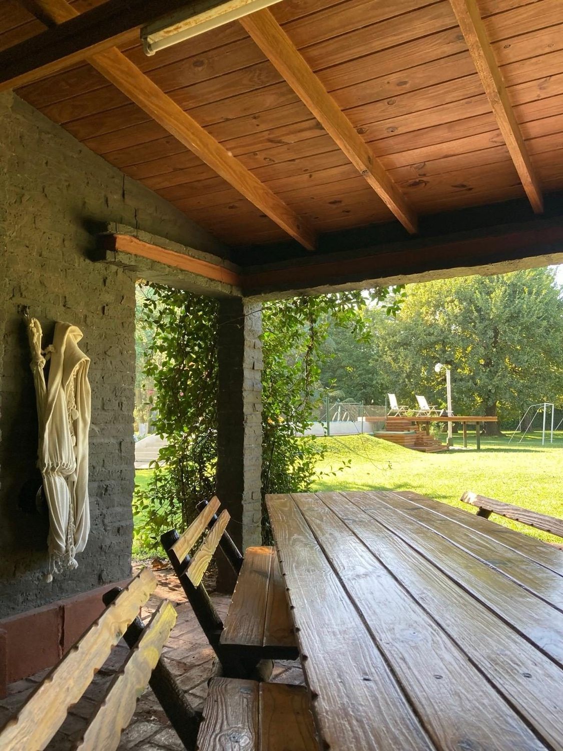 Galería con mesa larga de madera para comer al aire libre